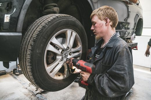 Auto Solve mechanic swapping a wheel with a cordless impact wrench during a seasonal tire changeover