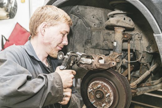 Mechanic compressing a brake caliper piston during service