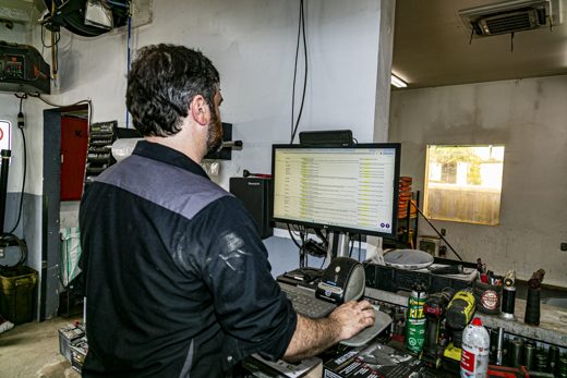 Auto Solve technician at the diagnostic computer reading fault codes behind a dashboard warning light