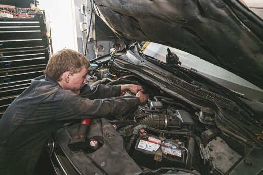 Auto Solve technician diagnosing an engine by flashlight at the independent shop in Creemore