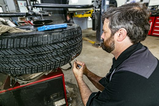 Auto Solve mechanic inspecting tire tread in the Creemore service bay