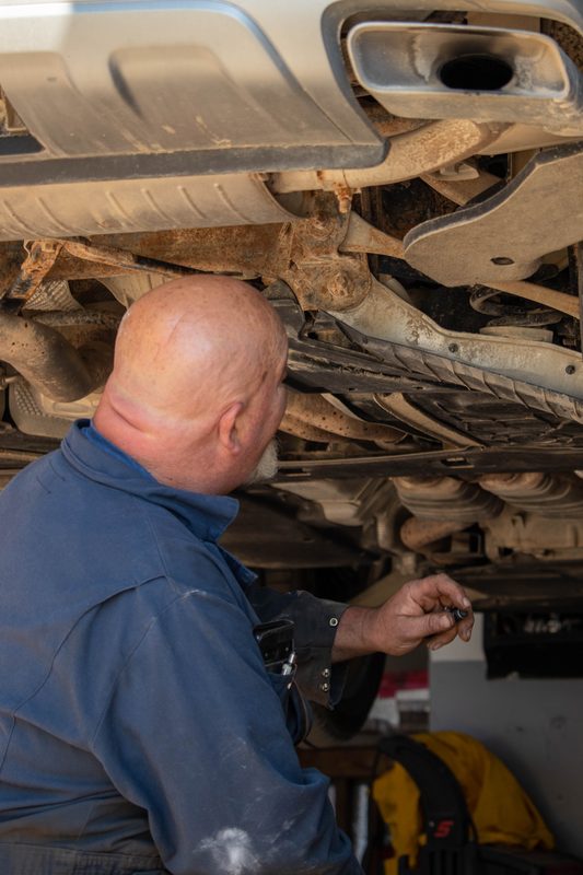 Mechanic carefully inspecting vehicle undercarriage