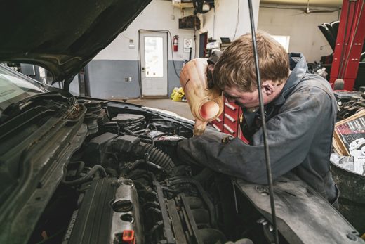Auto Solve technician topping up fluid under the hood during a service