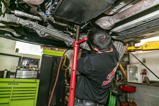 Auto Solve technician servicing a transmission and drivetrain from under a raised vehicle