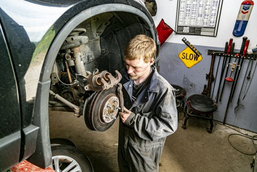 Auto Solve mechanic working on an SUV's front brakes to judge what's urgent and what can wait