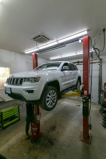 Vehicle raised on the two-post lift in the Auto Solve service bay for an oil change
