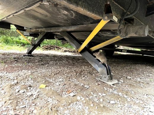 A mouse climbing an RV stabilizer jack up toward the underbody