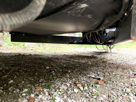 Exposed wiring hanging from a gap in the RV belly wrap