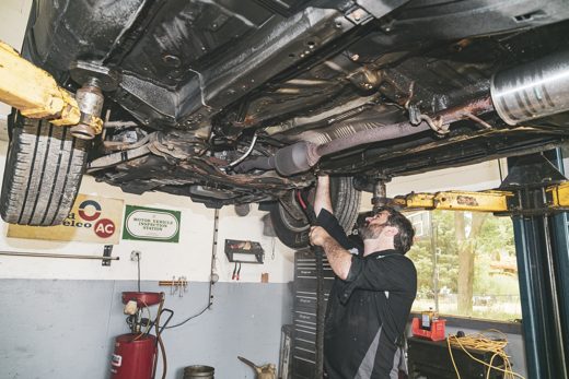 Technician photographing findings from under a raised vehicle during a digital inspection