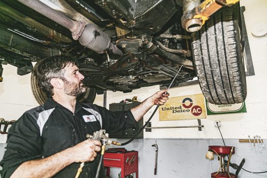 Technician inspecting a vehicle undercarriage before rustproofing
